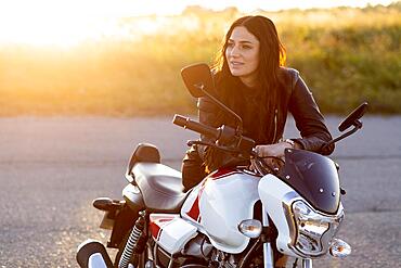 Smiley woman resting her motorcycle sunset