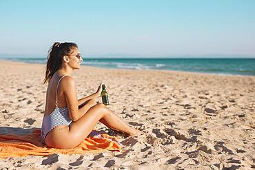 Smiling young woman relaxing beach with beer