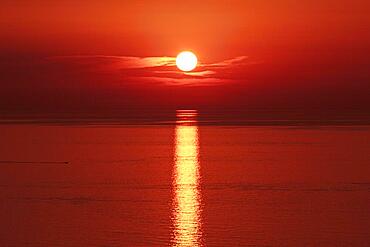 Sunset over the sea, the sun sinks into the sea on the horizon