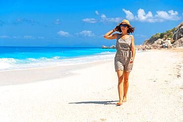 Portrait of woman with hat on Megali Petra beach with turquoise water of Lefkada island, Ionian Sea, Greece, Europe