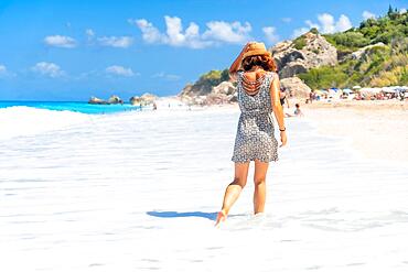 Woman walking through the water at Megali Petra beach with turquoise water of Lefkada island, Ionian Sea, Greece, Europe