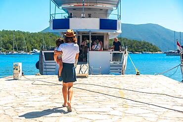 Woman tourist with her son getting on the boat in Fiskardo village on Kefalonia island, Greece, Europe