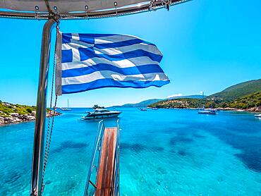 Greek flag on boat cruise around the island of Ithaki or Ithaca in the Ionian sea in the Mediterranean sea of Greece