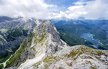 View from the summit of the Waxenstein over the rocky and narrow ridge of the Waxenstein ridge to the Eibsee lake and Hoellental, cloudy rocky mountain landscape, Wetterstein Mountains, Garmisch-Partenkirchen, Werdenfelser Land, Upper Bavaria, Bavaria, Germany, Europe