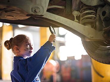 Little girl overall inspecting car with magnifier