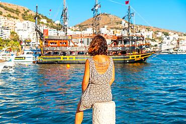 Woman looking at tourist boats at Saranda Beach on the Albanian Riviera in Sarande on Bulevardi Hasan Tahsini, Albania, Europe