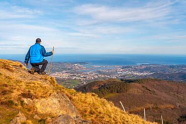 A young hiker looking at the views of the towns of Hondarribia and Hendaya from the mountains of Aiako Harria or Penas de Aya, Guipuzcoa. Basque Country