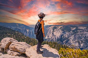 A young woman trekking at Sentinel Dome Lookout in Yosemite National Park looking at El Capitan Mountain. United States