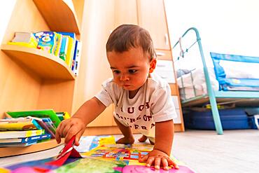 Young Caucasian mother playing with her in the room with toys. Baby less than a year learning the first lessons of her mother. Boy playing on the floor with toys