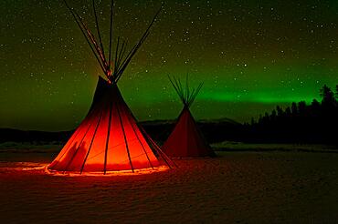 Two tents, tipis, Indian tents, front one illuminated from the inside, in a winter landscape, aurora borealis with stars in the sky, Yukon Territory, Canada, North America