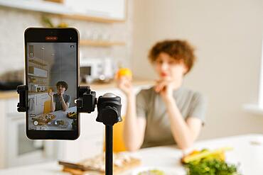 Professional nutritionist filming on her smartphone tutorial about healthy eating on her kitchen