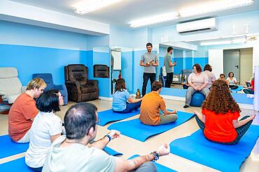 Rear view of a group of people with special needs in a yoga class