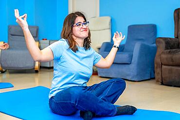 Woman with special needs enjoying during yoga class sitting in lotus position and arms raised