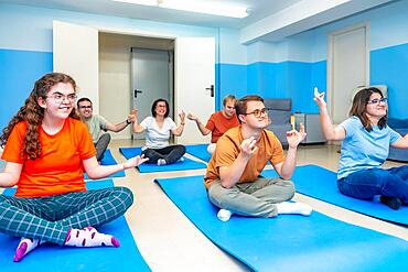 Disabled people enjoying practicing lotus pose during yoga class together