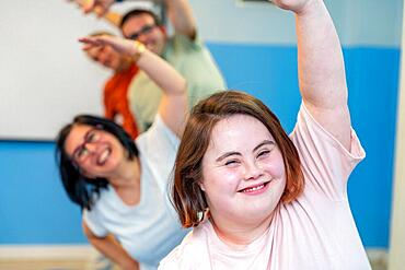 Happy group of people with special needs enjoying gymnastics stretching the back together