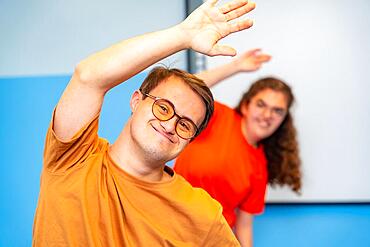 Man with down syndrome stretching and exercising with friends in the gym