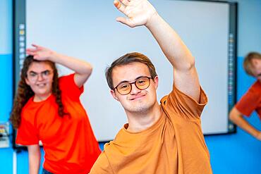 Man with down syndrome and mates in a gym standing stretching the back