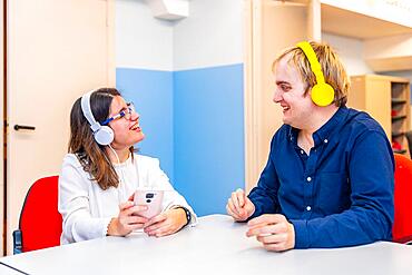 Mental disabled people using phone and listening to music sitting on a leisure room in a centre