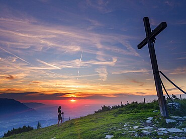 Young slim woman with hiking poles next to a summit cross at sunset, cirrus clouds in the sky, Schlenken, Bad Vigaun, Land Salzburg, Austria, Europe