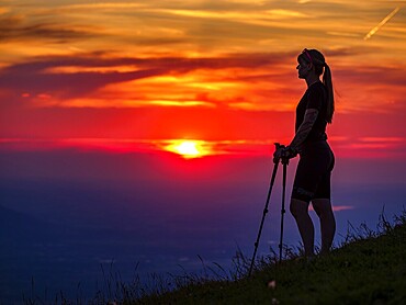 Silhouette of a young slender woman with hiking poles on a mountain meadow at sunset, Schlenken, Bad Vigaun, Salzburg province, Austria, Europe