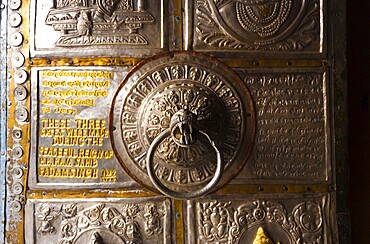 The ornamental metal door knocker and door at the entrance to Bhimakali Temple covered in inscriptions and reliefs in Sarahan, Himachal Pradesh, India. Horizontal