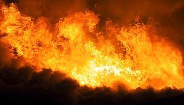 Arson or nature disaster, burning fire flame on wooden house roof