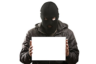 Criminal man in balaclava or mask covering face hand holding blank card white isolated