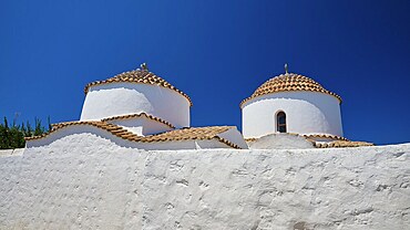 Two white-painted church towers with round, red-tiled roofs against a bright blue sky, Chora, Old Town, Patmos, Dodecanese, Greek Islands, Greece, Europe