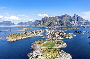 Aerial view over fishing village Henningsvaer, football stadium on rocky island, Lofoten, Norway, Europe