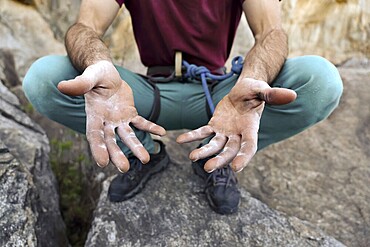 Close-up of a climber's hands showing the strength needed for rock climbing. The image highlights the texture and markings on the climber's gri