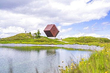 Reflection of a modern architectural building in a calm lake, surrounded by nature under a cloudy sky, Penken, Zillertal, Austria, Europe