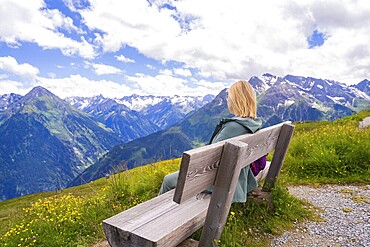 Woman sitting on a bench and enjoying the view of the mountain landscape under a clear sky, Penken, Zillertal, Austria, Europe