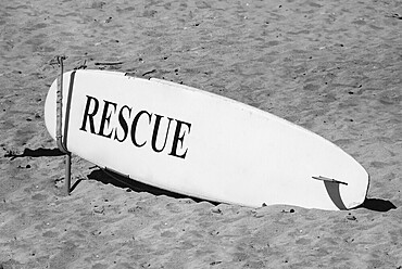 Close-up of a surfing board on the sand at the beach. Black and white photography