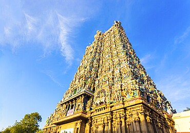 West tower gateway of Meenakshi Amman Temple covered in colourful statues of gods on a blue sky day at Madurai in south Indian state of Tamil Nadu, India, Asia