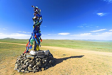 Small Buddhist stone stupa with prayer flags stands on the vast steppe in countryside Mongolia