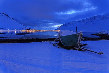 Boat in front of a fjord landscape, twilight, snow, illuminated city, mountains, Isafjördur, Westfjords, Iceland, Europe