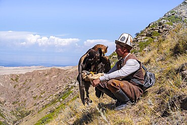 Traditional Kyrgyz eagle hunter with eagle in the mountains, near Kysyl-Suu, Kyrgyzstan, Asia