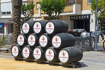 Several black barrels are stacked on a street in the city, Feria de la Manzanilla, Feria de Sanlúcar, Sanlúcar de Barrameda, Sanlucar, Cádiz, Cadiz, Andalusia, Spain, Europe