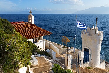 Small chapel on the coast with a view of the sea and a Greek flag, Church of Agios Nikolaos Krasoktistos, Agia Kyriaki, Nafplio, Nauplia, Nauplion, Nafplion, Argolis, Argolic Gulf, Peloponnese, Greece, Europe