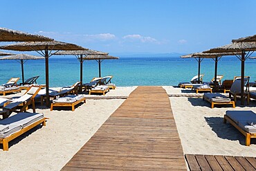 Wooden walkway leads to a sunlit beach with deckchairs and parasols by the clear sea, Lago Seaside Experience, Golden Beach, Pallini, Palioúri, Kassandra, Chalkidiki, Halkidiki, Central Macedonia, Greece, Europe