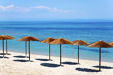 Sandy beach beach with thatched roofs and clear blue sea under a sunny sky, Golden Beach, Pallini, Palioúri, Kassandra, Chalkidiki, Halkidiki, Central Macedonia, Greece, Europe