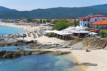 Beach with umbrellas and beach houses, clear blue water and mountains in the background, Sarti, Sithonia, Chalkidiki, Halkidiki, Central Macedonia, Greece, Europe