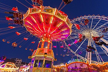 A funfair at dusk with illuminated chain carousel and Ferris wheel, Europa Rad, rides, wave flight, Cannstatter Wasen, folk festival, Bad Cannstatt, Stuttgart, Baden-Württemberg, Germany, Europe