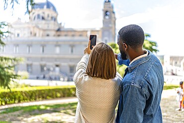 Rear view of a multi-ethnic couple taking a photo of a monument visiting a city