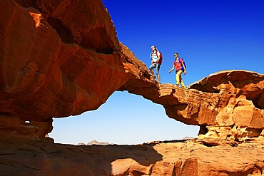 Couple hiking at Rock Arch, Al Borg Alsagheer, Wadi Rum, Jordan, Asia