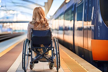 Woman in a wheelchair waiting for the train on the platform, surrounded by the warmth of the sunset, ai generated, KI generated, AI generated