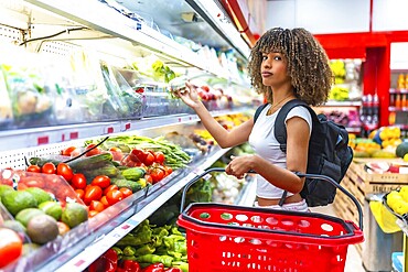 Latin curious beauty woman shopping fresh food in the supermarket in the vegetables section