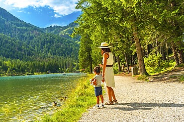 Tourists enjoying the scenic landscape of lake dobbiaco, surrounded by the majestic dolomites, during a sunny summer day in italy