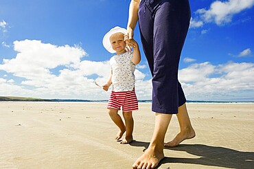 Little girl holding her mother's hand walking along a beach, Brittany, France, Europe