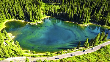 Aerial view capturing the stunning turquoise waters of alpine lake karersee reflecting the surrounding dolomites and coniferous forest